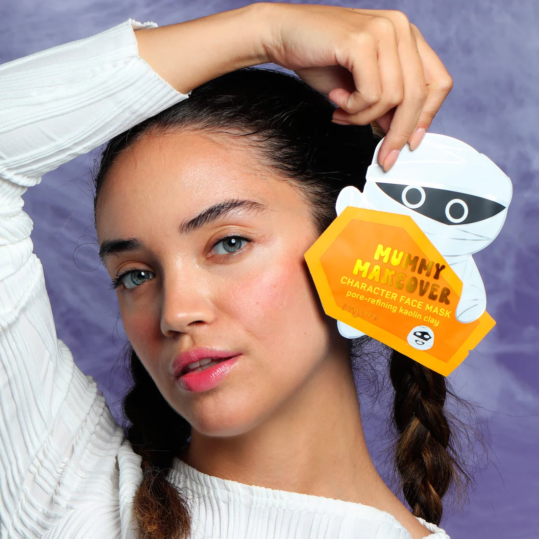 Mummy character face mask sachet held near woman’s head