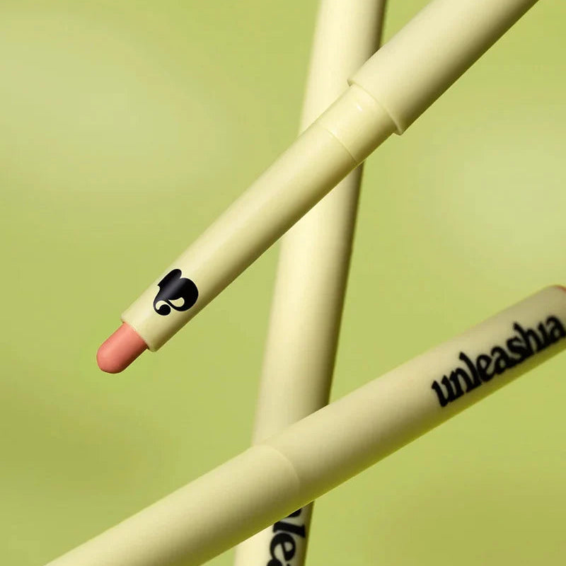Close-up of pale yellow lip pencil with pink tip, swatch near the tip