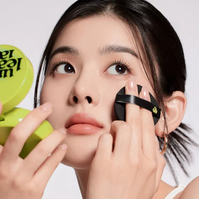 Green cushion compact with puff applicator near face for makeup application